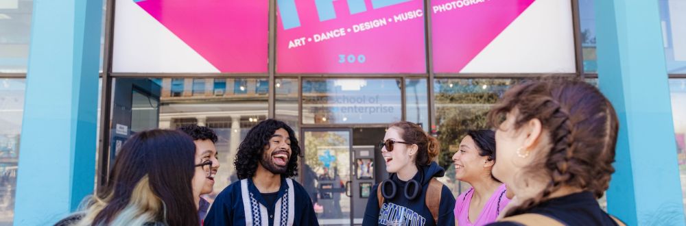 six students at tuition-free The School of Arts and Enterprise laughing together outside of the building’s front doors