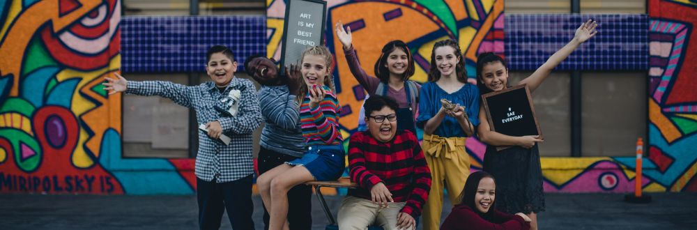 Eight middle school students from tuition-free The School of Arts and Enterprise pose in front of a school building