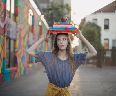 student at The School of Arts and Enterprise tuition-free charter school walking outside balancing books on her head