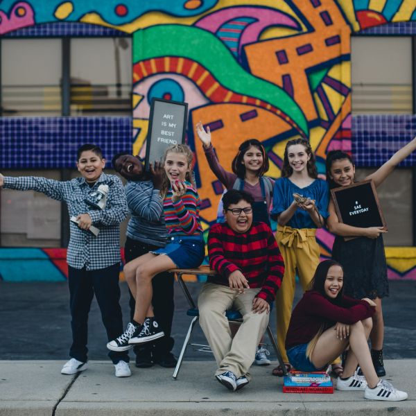 Eight middle school students from tuition-free The School of Arts and Enterprise pose in front of a school building