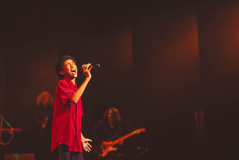 students sings into microphone on stage